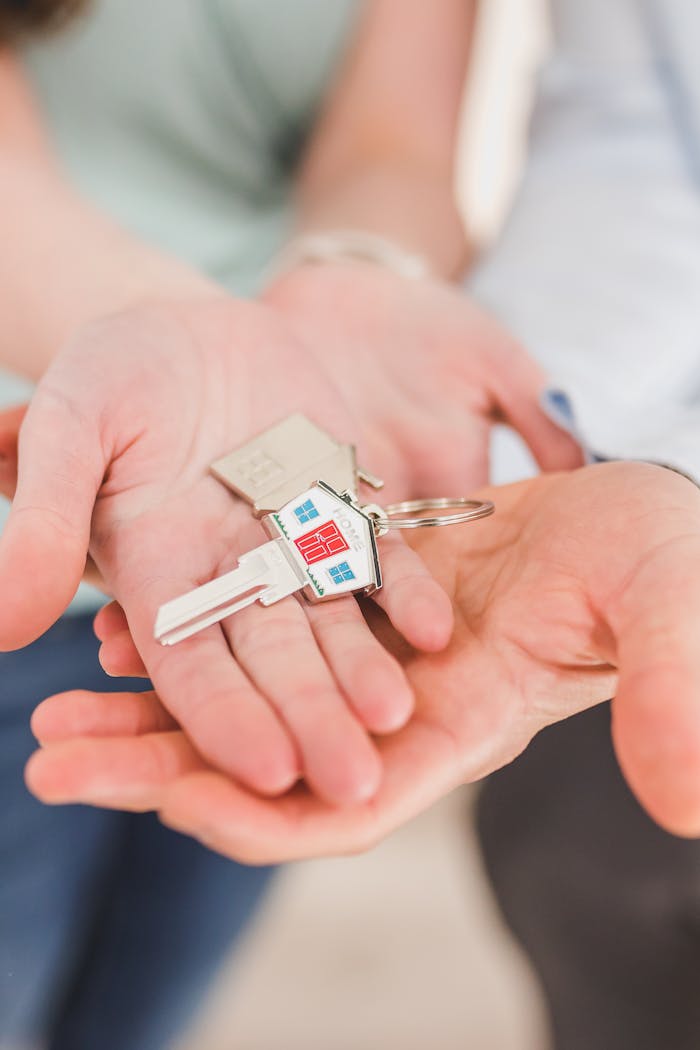 digital Close-up of hands holding a key with a house-shaped keychain, symbolizing new beginnings.
